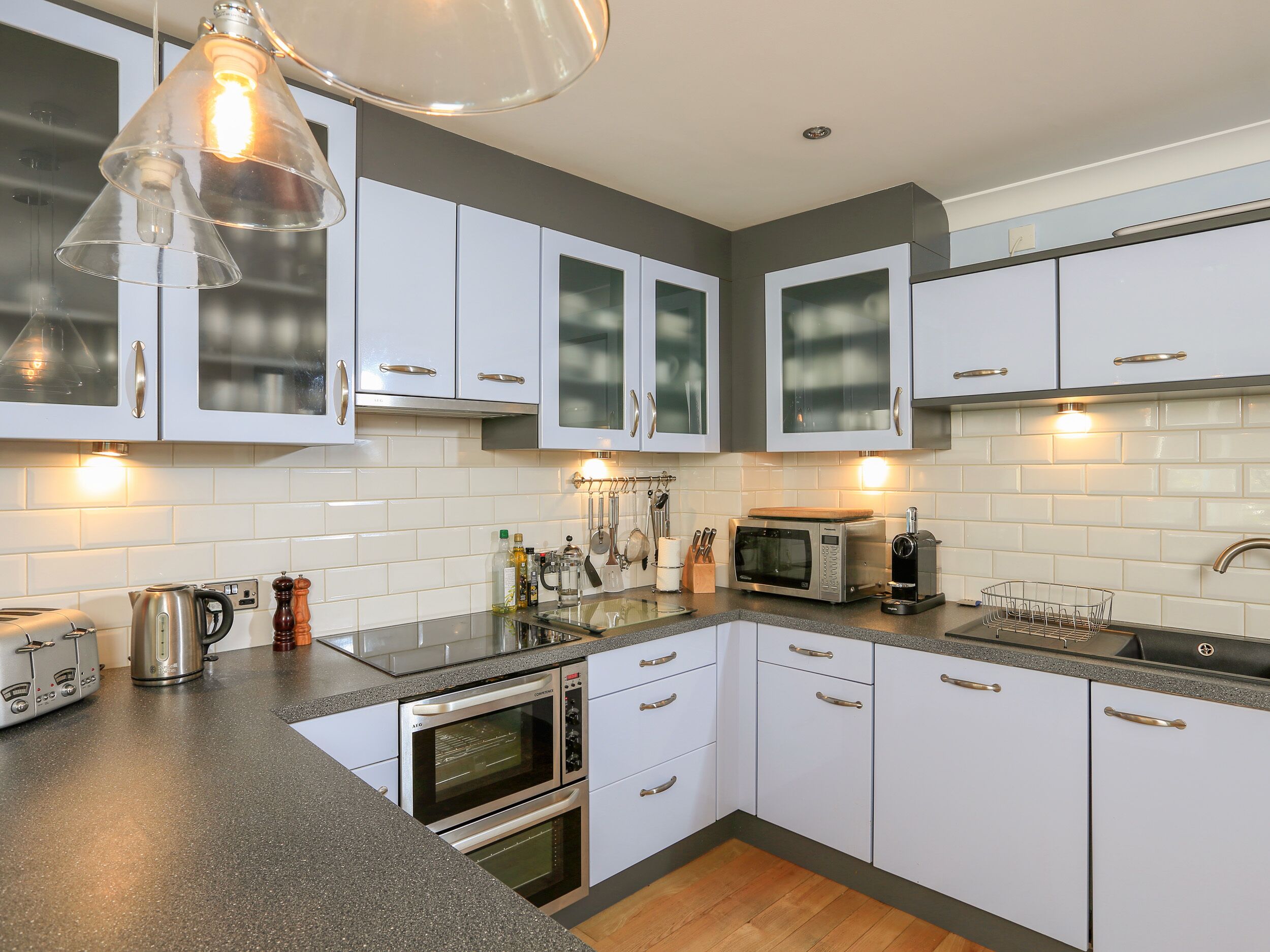Een moderne keuken met witte kasten, een magnetron, een waterkoker en een broodrooster.