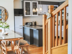 Una cocina moderna con una isla central, armarios blancos y una escalera de madera.