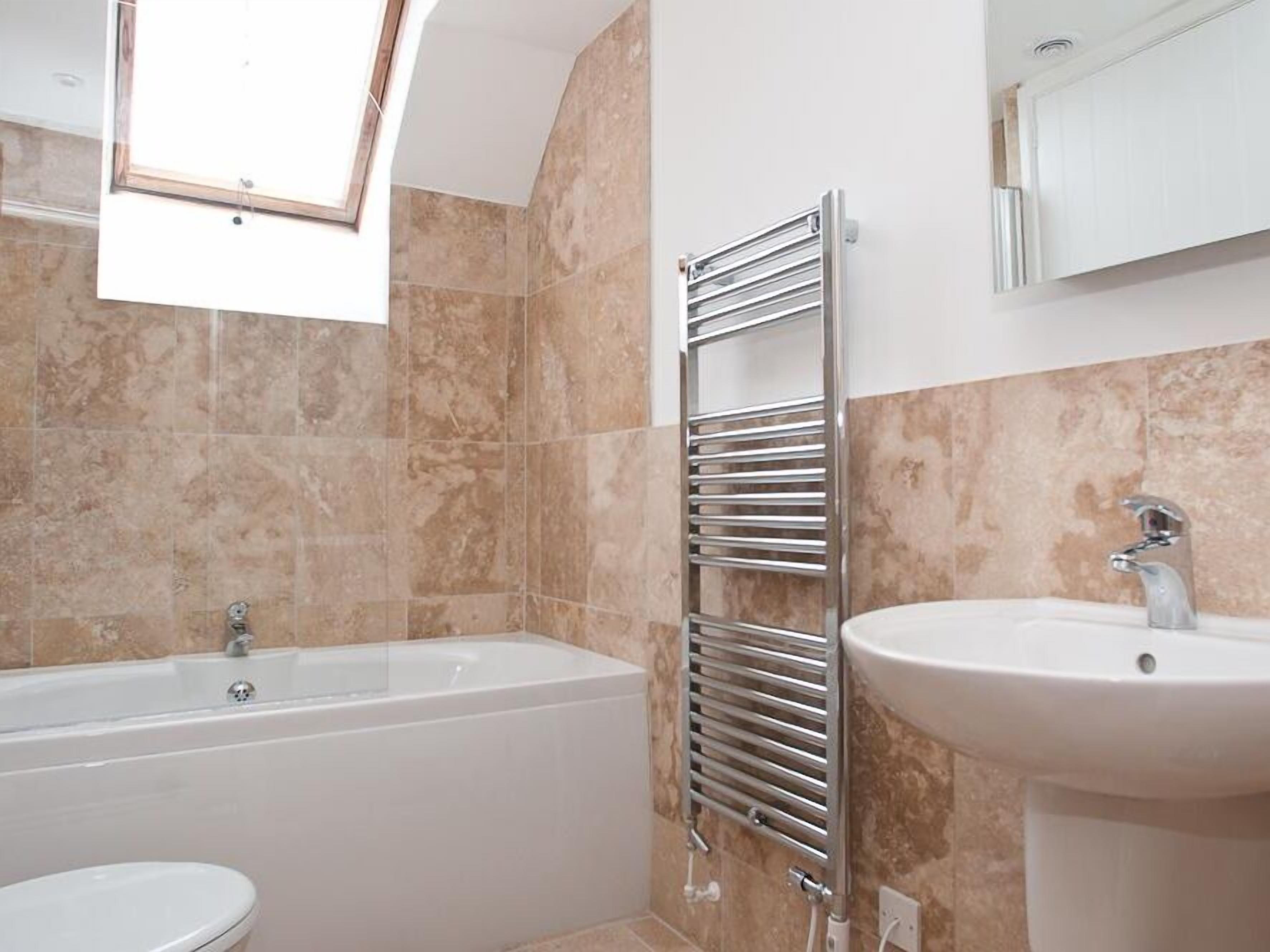 Une salle de bain avec une baignoire, un lavabo et un porte-serviettes.