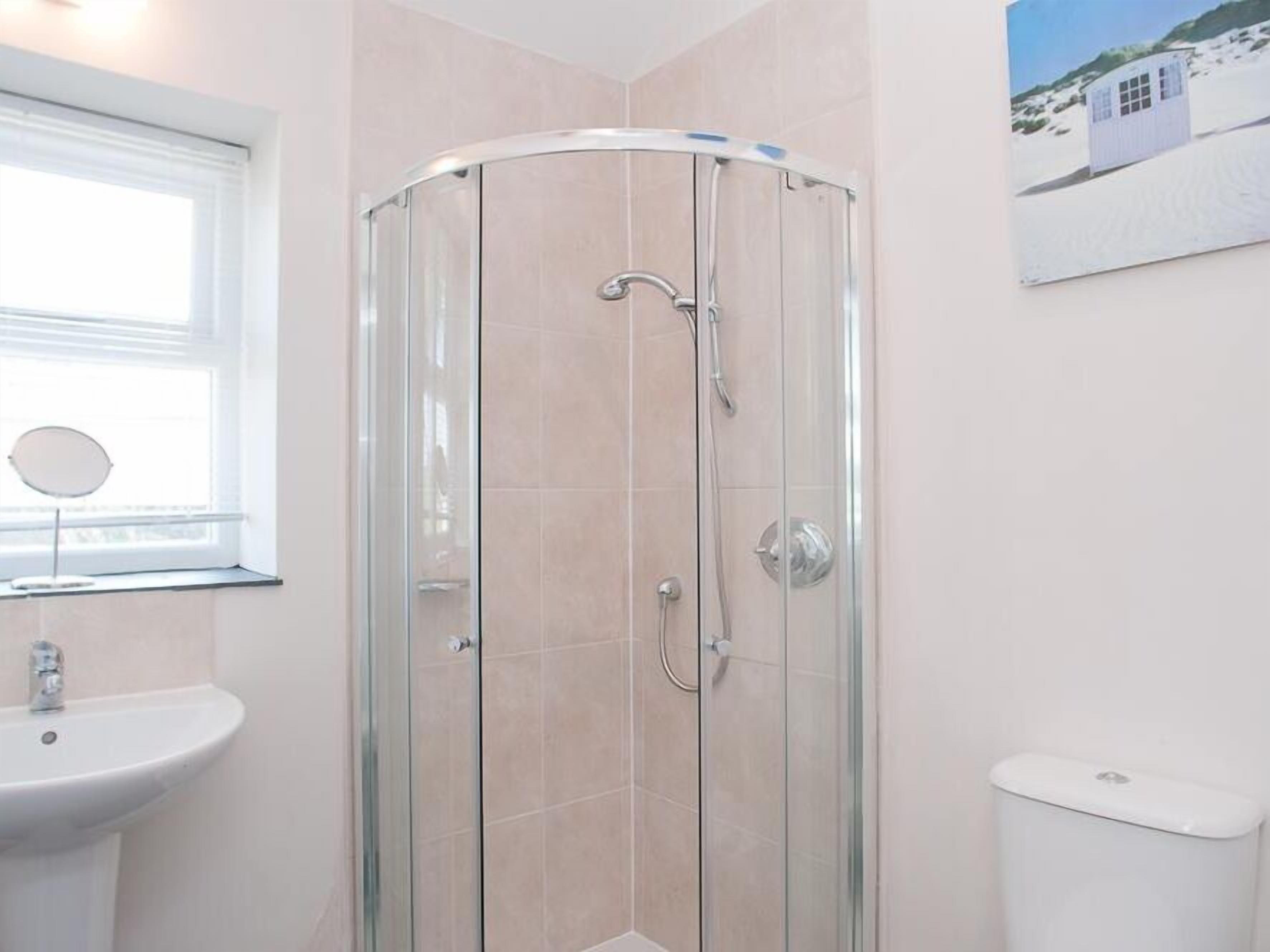 Et badeværelse med bruseniche, håndvask og toilet.