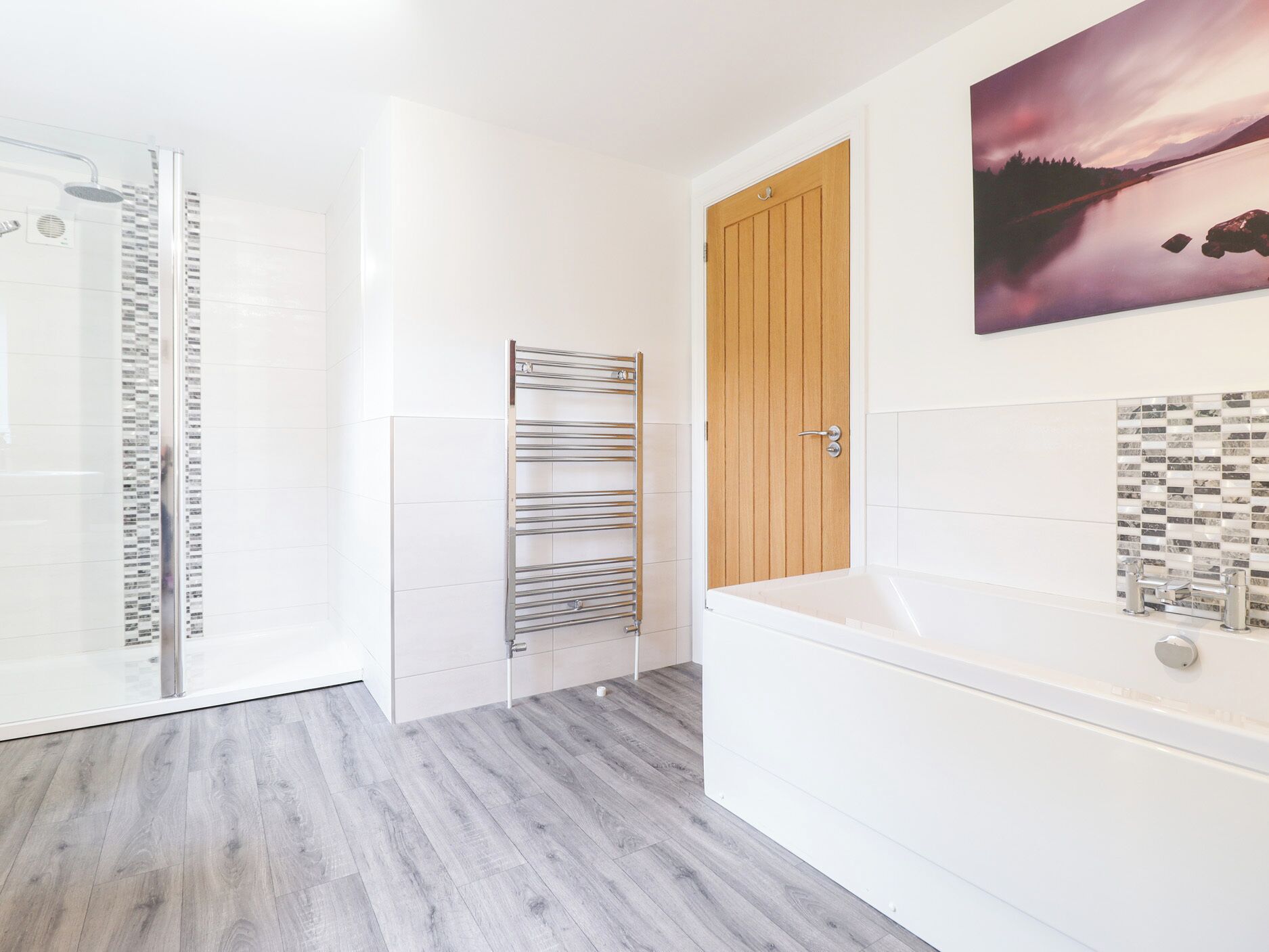 Un baño moderno con puerta de madera, cabina de ducha de vidrio, bañera blanca y salpicadero de azulejos.