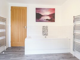 A bathroom with a wooden door, a white bathtub, and a wall-mounted towel rack.