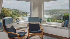 A room with two large windows offering a view of a coastal landscape. - Dolphins (Salcombe)