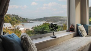 A room with a large window overlooking a coastal landscape, a globe, and a copper lantern on the windowsill. - Dolphins (Salcombe)