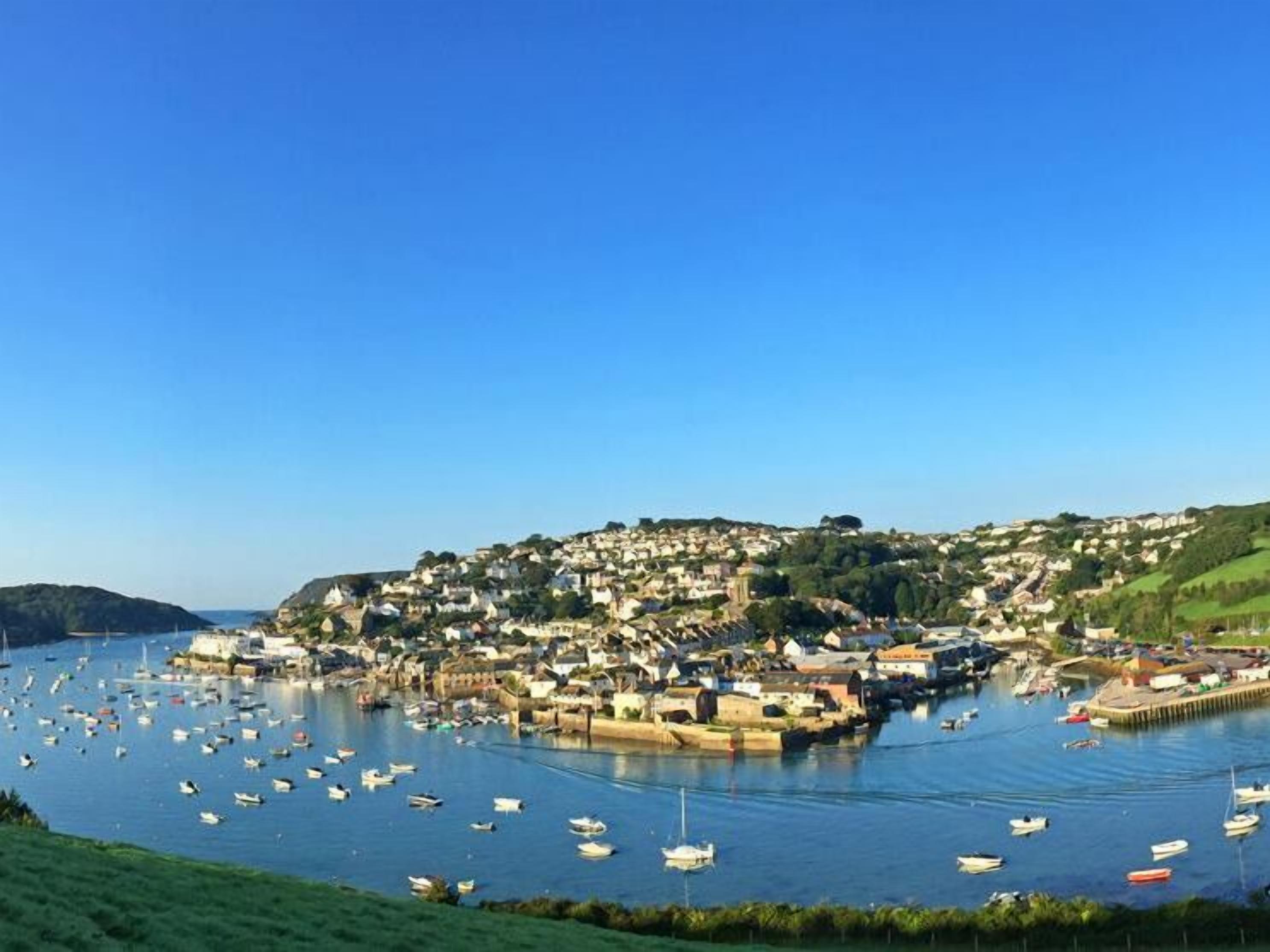 Un poble costaner amb un port esportiu ple de vaixells, envoltat d'edificis residencials i vegetació.