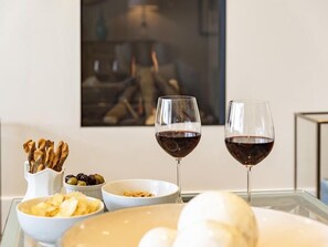 A dining table with two wine glasses, bowls of snacks, and a decorative vase. - Quayside (Salcombe)