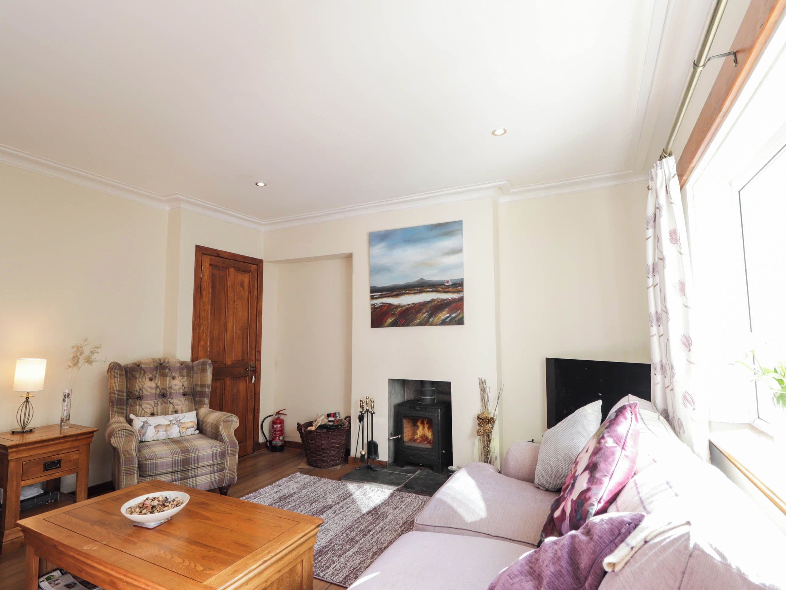 A cozy living room with a sofa, a wooden coffee table, a fireplace, and a painting on the wall.