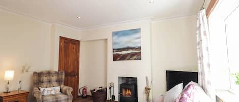 A cozy living room with a sofa, a wooden coffee table, a fireplace, and a painting on the wall.
