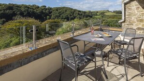 A terrace with a table and chairs, overlooking a scenic landscape. - 5 Fairhaven (Salcombe)