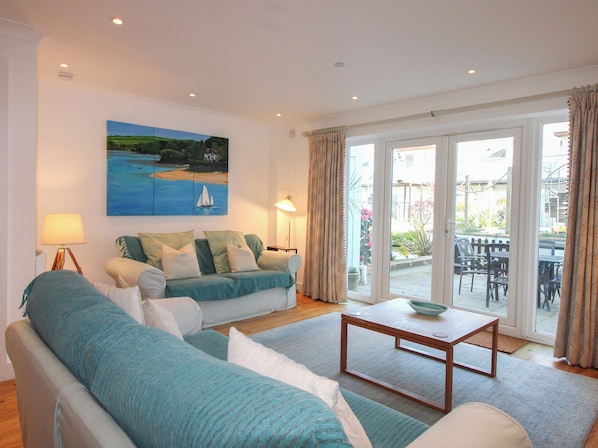 A living room with a sofa, a coffee table, and a painting of a sailboat on the wall.