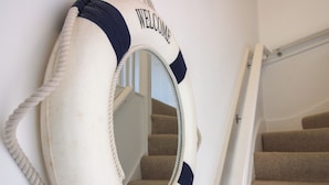 Un flotador con el texto 'WELCOME' y 'ABOARD' en una pared junto a una escalera.