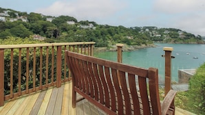 Terraza de madera con vistas a la costa, incluyendo casas y barcos.