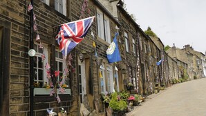 A row of stone buildings with flags and flowers.
