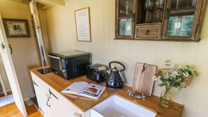 A kitchen with a wooden countertop, a white sink, a kettle, a toaster, and a framed inspirational quote on the wall.