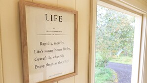 A framed quote on a wall with a view of a garden outside.