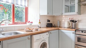 A kitchen with a washing machine, a coffee maker, and a microwave.