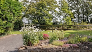 A stone wall with a metal sign, surrounded by various plants and flowers.