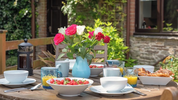 A breakfast table with a variety of dishes, including a bowl of strawberries, a pitcher of orange juice, and a plate of pastries.