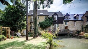 Een woonhuis met een vijver, een houten pergola en een pad van natuursteen.