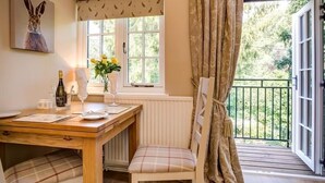 Een eethoek met een tafel, stoelen, een fles wijn en een vaas met bloemen.