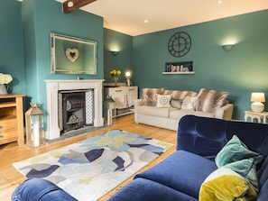 Uma sala de estar com paredes verde-água, lareira, sofá e poltrona azul.