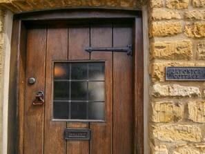 A wooden door with a window and a nameplate reading "Japonica Cottage".