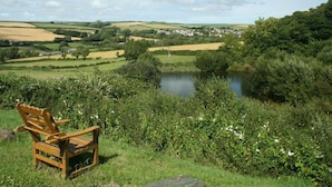 A bench overlooking a pond with a village in the background. - Cowslip Cottage (Kingsbridge)