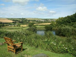A bench overlooking a pond with a village in the background.