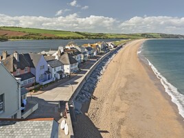 Un pueblo costero con una playa arenosa, casas de techos de paja y una vista despejada del mar.