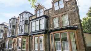 A row of traditional stone houses with bay windows and multiple stories. - The Haven (Buxton)