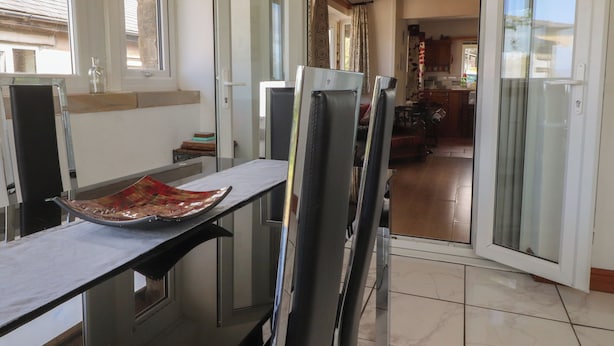 Un comedor con una mesa, sillas y una puerta de vidrio que da a la cocina.