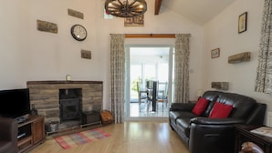 Una sala de estar con chimenea, sofá de cuero, piso de madera y televisor.