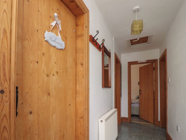 A hallway with wooden doors, a radiator, and a sign reading "Bathroom". - Pendleside (Clitheroe)