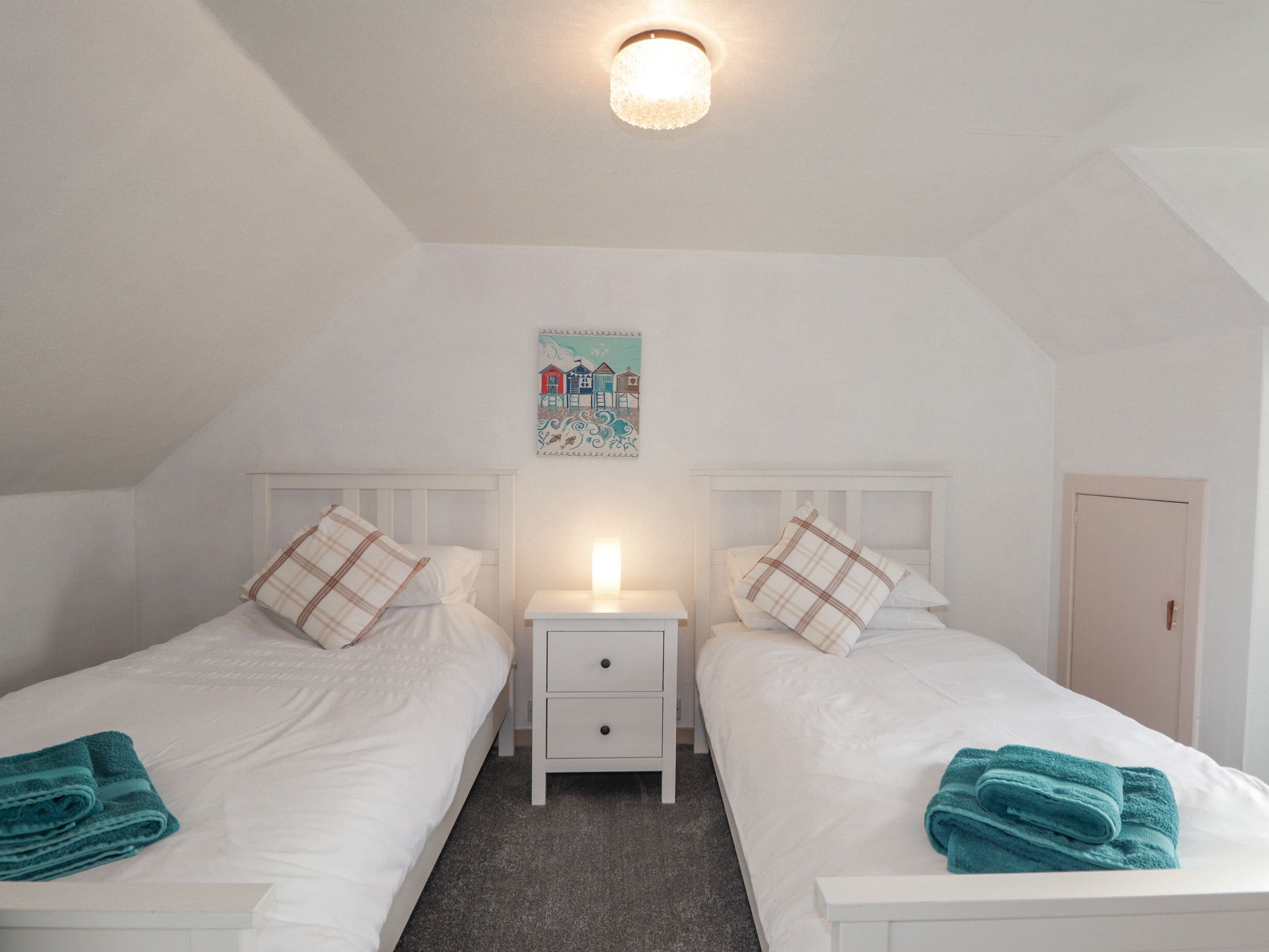 Une chambre double avec deux lits, une table de chevet, une décoration murale et une porte.