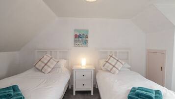 Une chambre double avec deux lits, une table de chevet, une décoration murale et une porte.