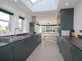 A modern kitchen with grey cabinets, a stainless steel sink, and a skylight.