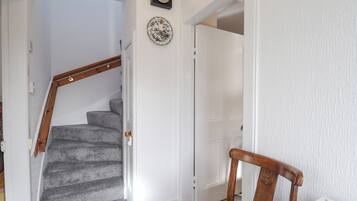 A staircase with carpeted steps leading to a white door. A wooden chair is positioned near the door.
