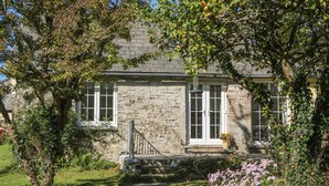 A stone house with a small porch, a window, and a door. - The Daffodil Shed (Yelverton)