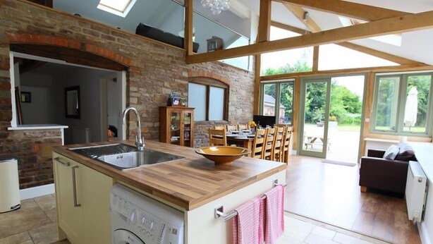 Una cocina con lavadora incorporada, encimera de madera y zona de comedor con sillas y mesa.
