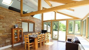 Un comedor amplio con pared de piedra, vigas de madera y un ventanal grande.