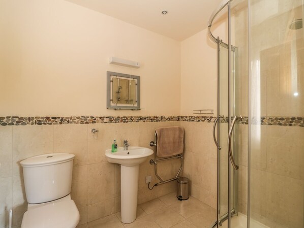 A bathroom with a toilet, sink, and glass shower enclosure. - Burnside Lodge (Pitlochry)