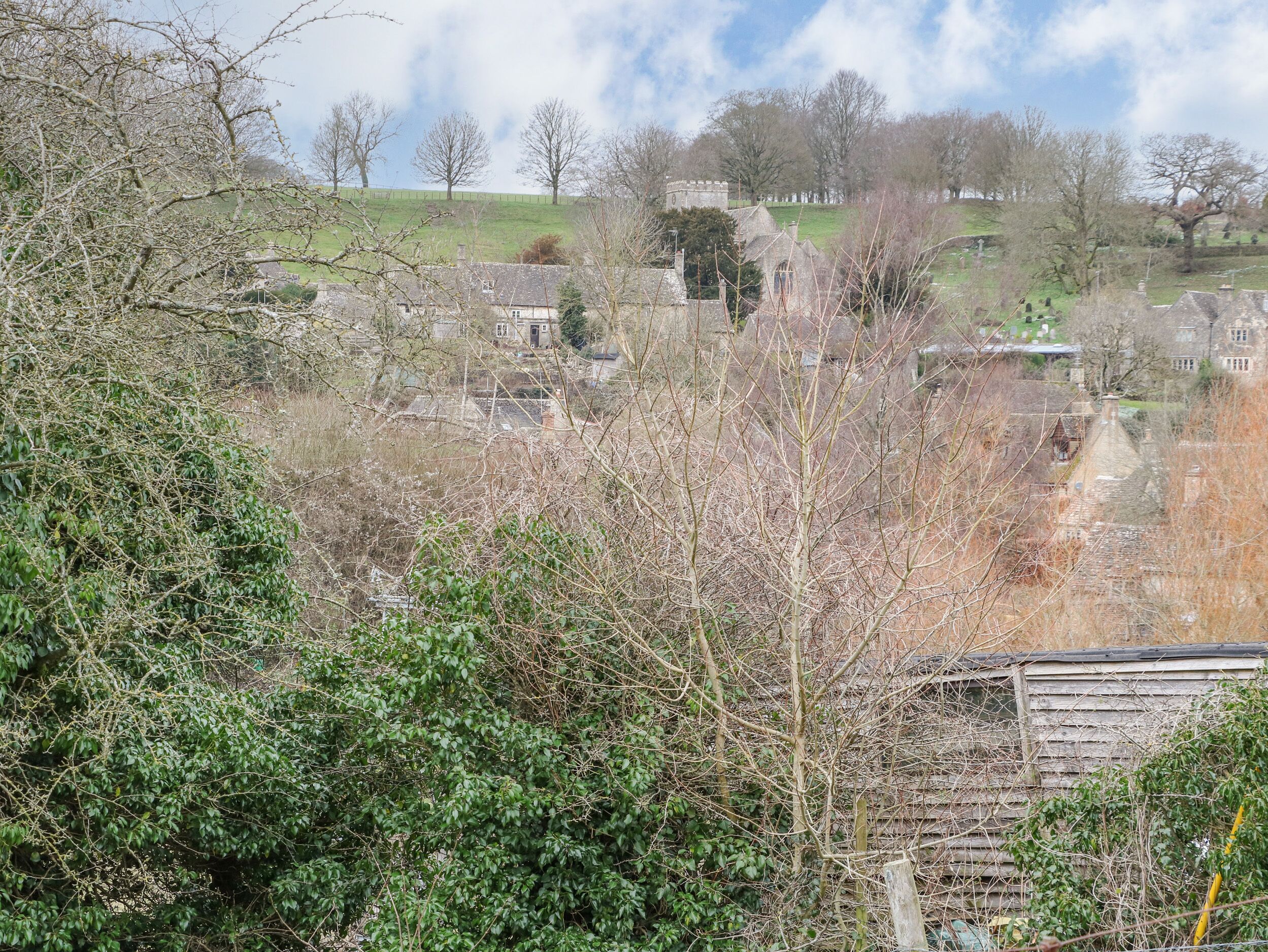 A rural landscape with stone buildings, a hill, and a clear sky.
