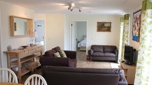 A living room with a sofa, a television, and a wooden table. - The Milking Parlour (Salisbury)