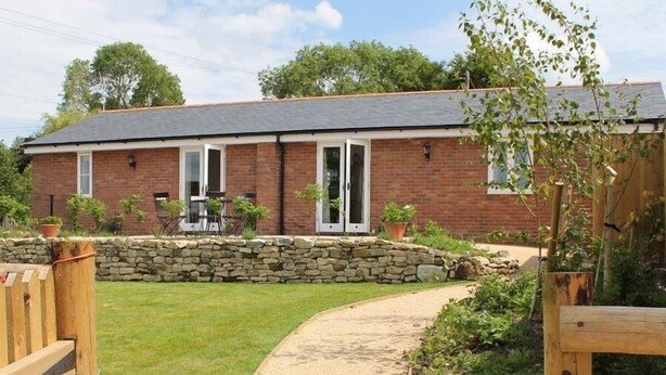 A two-story brick house with a stone wall and a paved driveway. - The Milking Parlour (Salisbury)