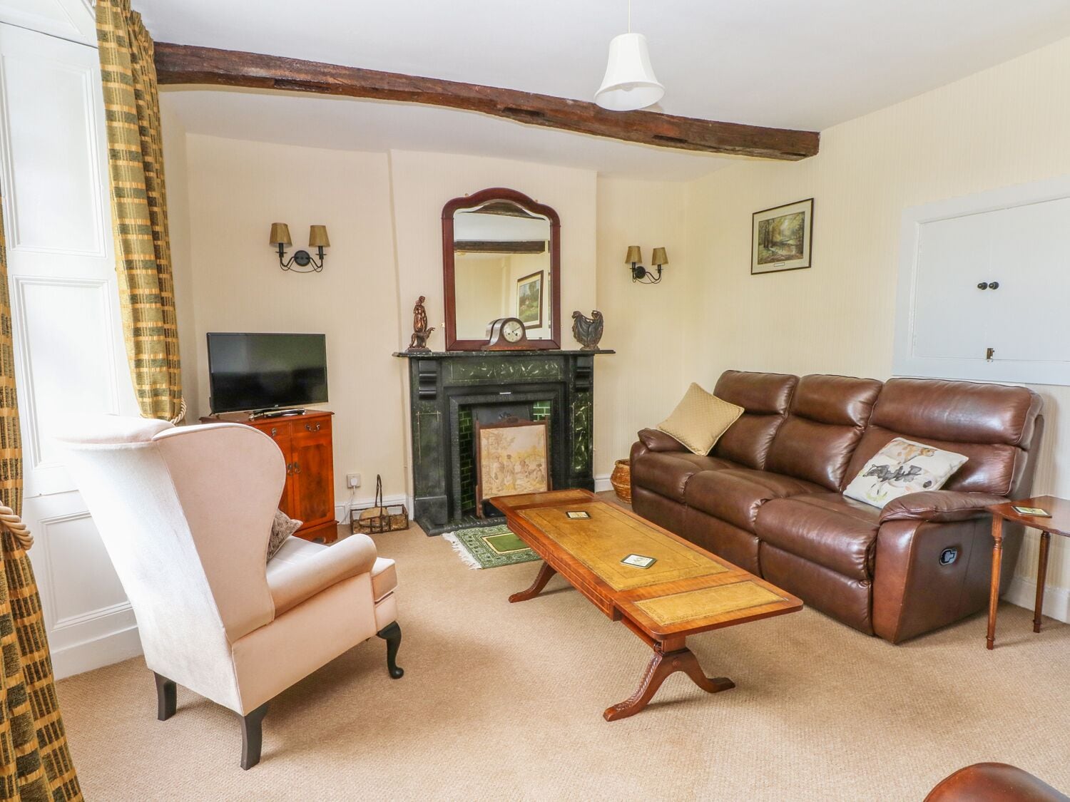 A living room with a sofa, armchair, wooden coffee table, fireplace, and a television.