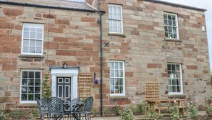 A stone building with a front door, windows, and a patio with outdoor furniture. - Godscroft Hall (Frodsham)