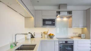 Una cocina moderna con horno empotrado, microondas y lavabo.