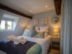 Relax in this cozy loft-style room with a comfortable bed, bedside table, and beautiful views of the surrounding greenery.