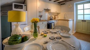 Un comedor con una mesa preparada para cuatro, microondas, pileta y ventana con vistas.