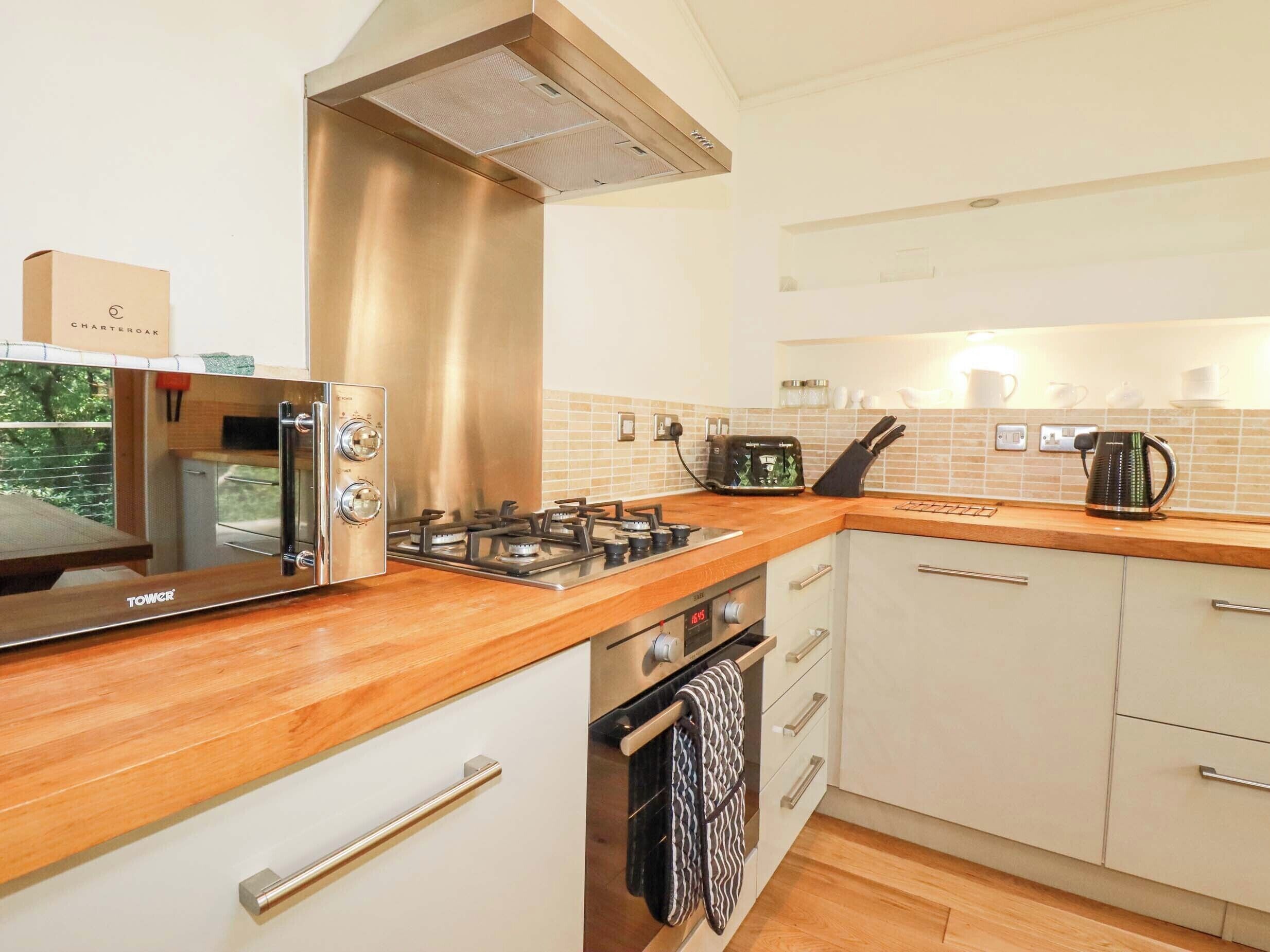 A modern kitchen with a stainless steel range hood, a built-in oven, a microwave, and a gas stove.
